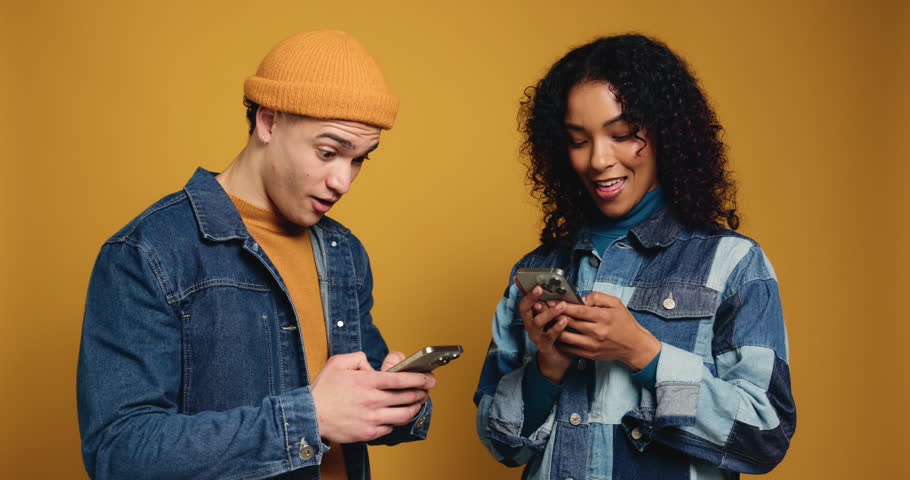 Couple, phone and happy with high five in studio for celebration, goal or online prize on yellow background. Gen z man, woman and excited on smartphone, success or mobile app for competition giveaway