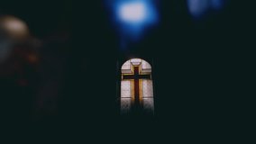 Golden stained glass cross window isolated in dark cathedral interior, emphasizing Christian spiritual symbolism and historic sacred architectural design - Powered by Shutterstock - Get 15% off with code: PIKWIZARD15