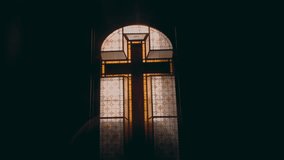 Golden stained glass cross window centered in dark cathedral interior with intimate close up view, representing Christian sacred architecture and spiritual heritage - Powered by Shutterstock - Get 15% off with code: PIKWIZARD15