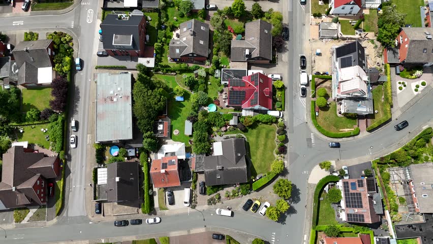 Aerial flyover small american city village at sunny day. Cars on street. Top down shot. Green trees at sunset in summer. Calm and peaceful town in United States. Solar panels on rooftop.