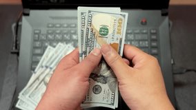 Man counting 100 dollar bills on a laptop keyboard. Earning with internet with online business , make money online concept - Powered by Shutterstock - Get 15% off with code: PIKWIZARD15