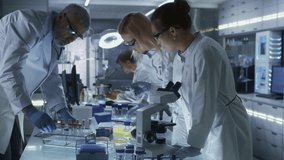 Medical Laboratory Scientists in White Coats Work at Lab Benches Using Pipettes, Microscopes, Test Tubes. Team Examines Biological Samples, Records Data, Operates Scientific Equipment and Research - Powered by Shutterstock - Get 15% off with code: PIKWIZARD15