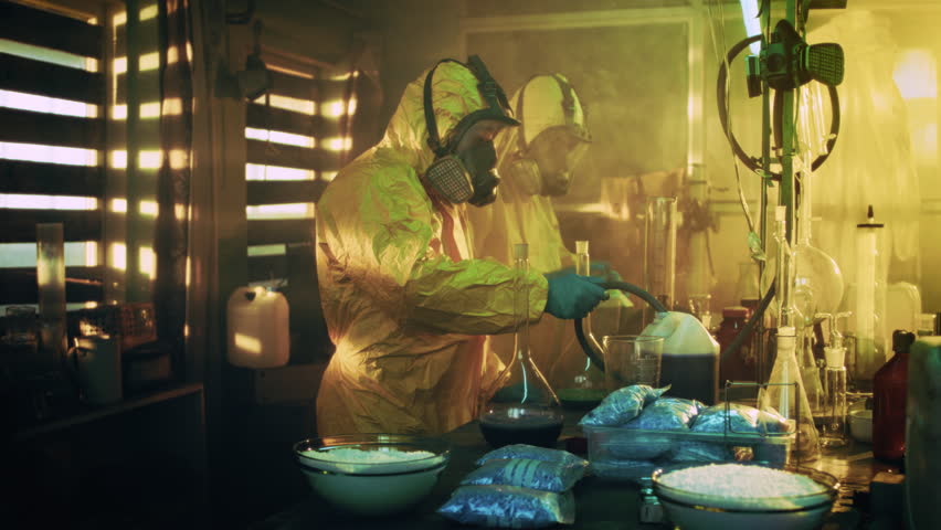 In the Underground Drug Laboratory Clandestine Chemists Wearing Protective Masks and Coveralls Mix Chemicals for Synthesising New Batch of Addictive Narcotics. They Work in the Abandoned Building.