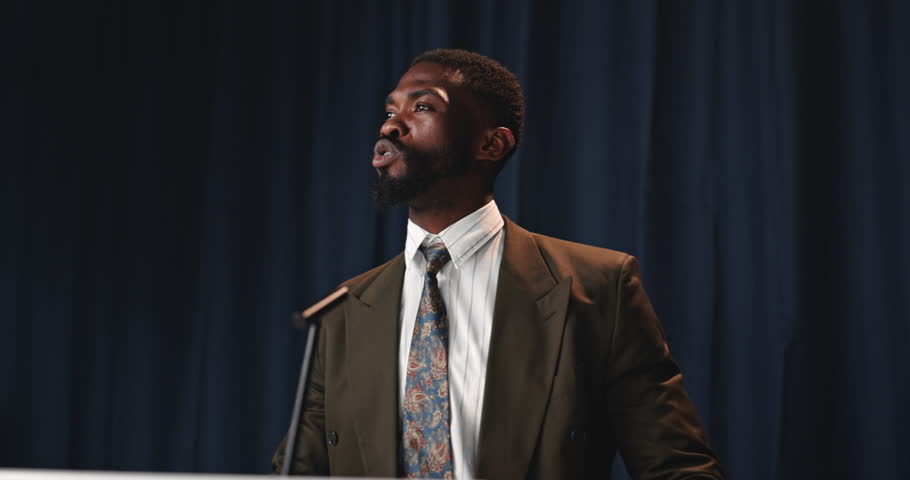 Speech, man and politician on a stage for election, democracy or political campaign. Talking, microphone and male speaker at conference, meeting or seminar for vote for activism by podium in hall.