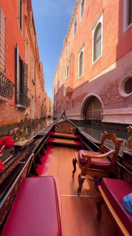 POV ride on a Venetian gondola gliding through calm canals. No people, only the bow of the boat and gentle ripples. Vertical video capturing peaceful, timeless Venice from a slow perspective.
