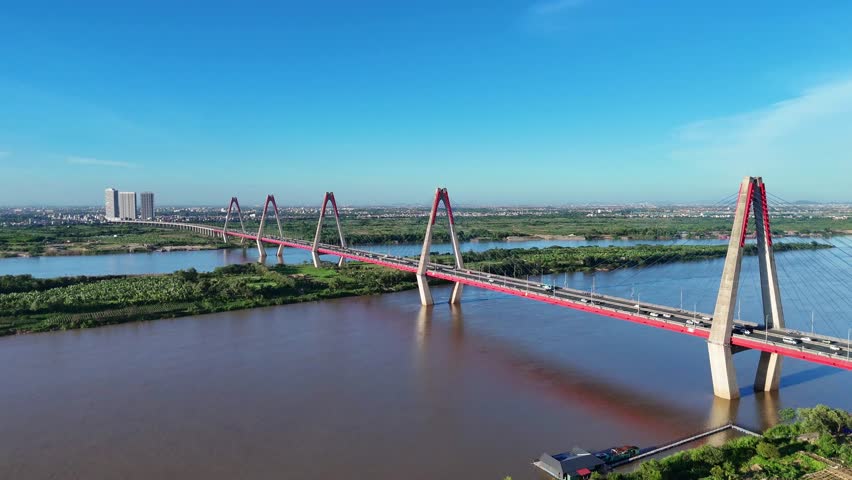 An aerial view of Nhat Tan Bridge in Hanoi, Vietnam, showing its striking cable-stayed design stretching across the Red River, with vehicles in motion