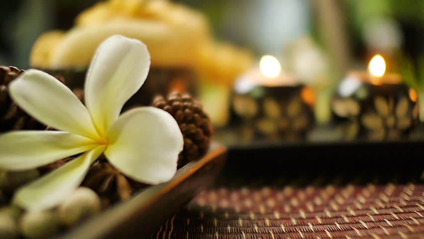 Close‑up of decorative candle holders with floral carvings and lit candles, surrounded by spa elements including plumeria flower, natural textures, and warm relaxing ambiance - Powered by Shutterstock - Get 15% off with code: PIKWIZARD15