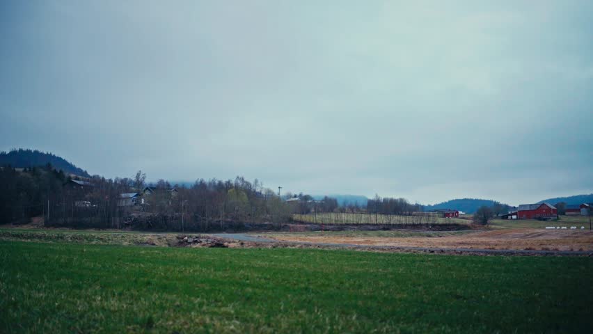 Car Passes On The Road Overlooking A Rural Village In Norway. Timelapse