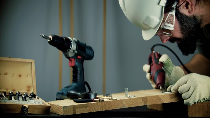 Construction Worker Using Power Tool.  Carpenter In Hard Hat And Safety Glasses. Woodworking Craft DIY Renovation. Skilled Laborer Power Tools. Building And Carpentry. Handyman Tool Use Workshop Tools