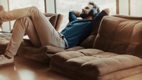 Man Relaxing On Sofa With Headphones. Male Enjoying Music. Leisure Time And Entertainment. Mental Wellness And Stress Relief Listening To Podcast. Cozy Living Room Audio Therapy Home Comforts Day Off - Powered by Shutterstock - Get 15% off with code: PIKWIZARD15