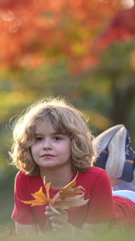 Autumn Child Face. Kid hold Fall Yellow Leaves. Little Child In Beautiful Autumn Park Outdoor. Kids play in autumn park. Child boy with oak maple leaf. Fall foliage. Kids play in autumn fall.