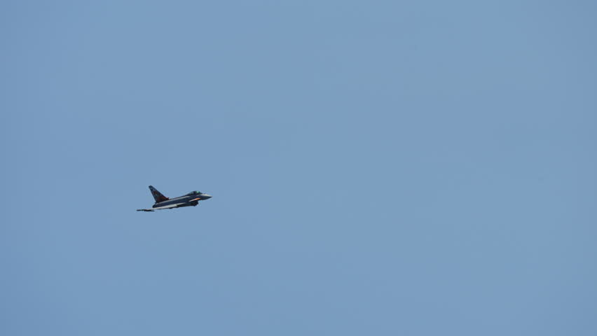 Military jet fighter executing a fast roll maneuver in the sky during flight performance