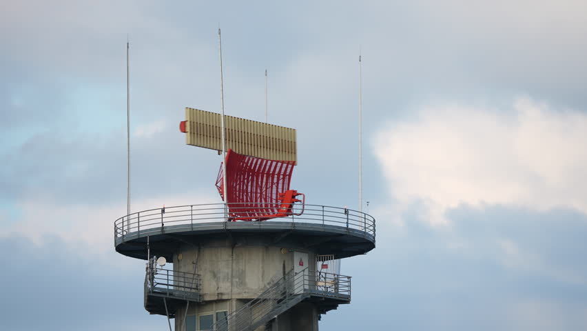 Detailed view of airport radar system with red rotating antenna mounted on tall tower