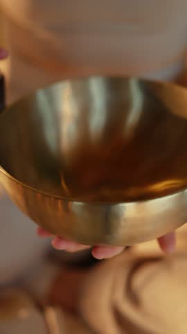 Hands holding and playing singing bowl