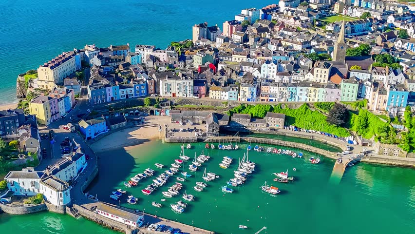 A receding and then a rotating aerial view across the harbour in the early morning in Tenby, South Wales in summertime