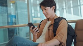 Happy young Asian man waiting for departure at the airport terminal while using his phone, social media, internet - Powered by Shutterstock - Get 15% off with code: PIKWIZARD15