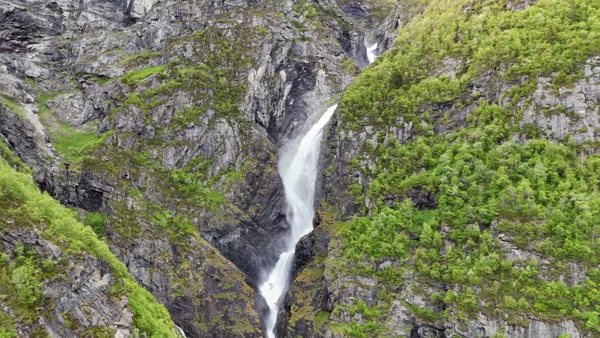 An Aerial view of a majestic waterfall cascading through the lush Eikesdal valley in scenic Norway