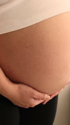 Close up of big pregnant belly of caucasian woman in white tank top