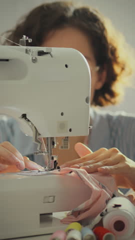 Focused on her work, a woman operates a sewing machine, creating with soft fabric in a warm and inviting craft room filled with natural light during a quiet afternoon