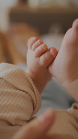 In a warm and inviting living room, young parents lie on a sofa, lovingly touching their child's legs and feet. The moment captures joy and connection in family life