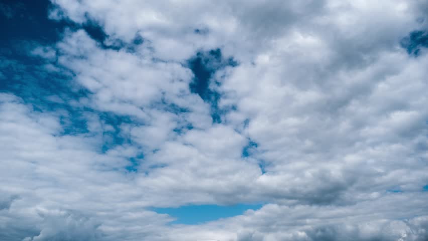 Time-lapse shows serene white clouds moving gracefully across a vast, deep blue sky, gradually revealing more of the clear expanse behind them as they drift and dissipate in the atmosphere.