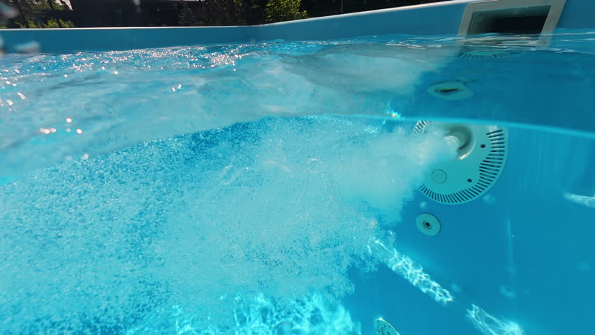 Swimming pool with active counterflow system creating strong water jets and bubbles underwater.