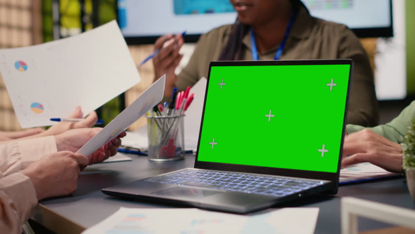 Group of businesswoman looks at isolated mockup on laptop, briefing session meeting in a modern boardroom setting. Corporate reports for presentations and resources analysis. Camera B.