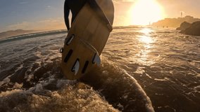 LENS FLARE, SLOW MOTION: Following female surfer with wooden surfboard through shallows at sunset. She came out of water after surf session and is walking along the shore, bathed in golden setting sun - Powered by Shutterstock - Get 15% off with code: PIKWIZARD15