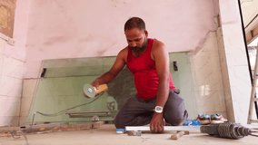 Mason Uses Power Cutter on Ground Level Panel, Skilled Laborer Works over Alloy Frame Inside shop, Fabricator Shapes Aluminum Bar with Precision Tools, Worker strikes metal pipe gently to position it - Powered by Shutterstock - Get 15% off with code: PIKWIZARD15