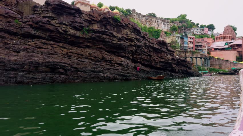 Colorful Riverside Town with Hillside Temples and Boats, Traditional Shrine Amidst Lush River Valley, Scenic Tourism Destination on Riverfront Cliff, Cultural Hub Hosting vivid Buildings plus vessels