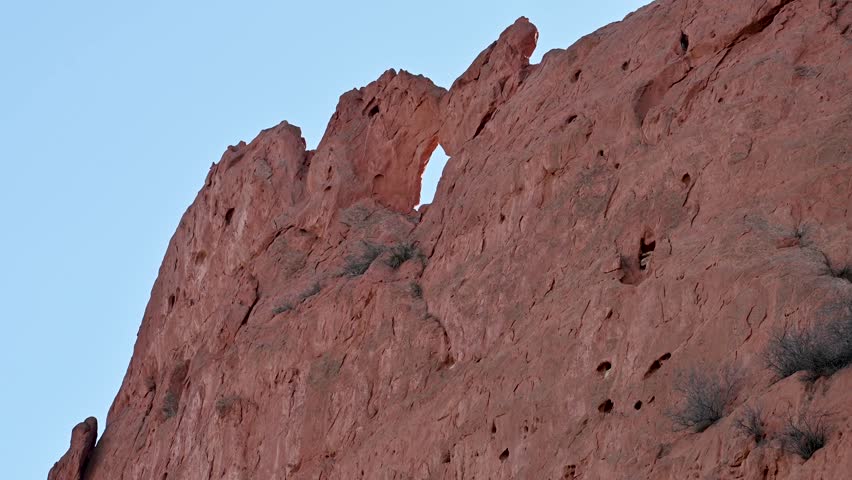 Close-up of rugged red sandstone rock wall featuring a natural arch formation at Garden of the Gods, Colorado.