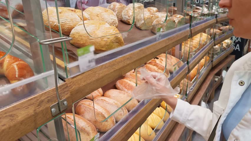 Stocking Shelves In Supermarket. Freshly Baked Products In A Bakery. Grocery Shopping For Fresh Bread. Artisan Loaves. Rye Bread And Multigrain. Customer Choosing Loaf Of Bread. Baked Goods In Store