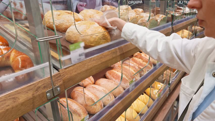 Stocking Shelves In Supermarket. Freshly Baked Products In A Bakery. Grocery Shopping For Fresh Bread. Artisan Loaves. Rye Bread And Multigrain. Customer Choosing Loaf Of Bread. Baked Goods In Store