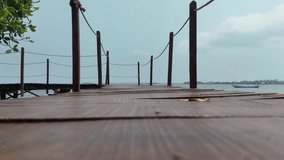 Low angle ground-level perspective view along a wooden pier with rope railings leading out over a calm sea on a tranquil day - Powered by Shutterstock - Get 15% off with code: PIKWIZARD15
