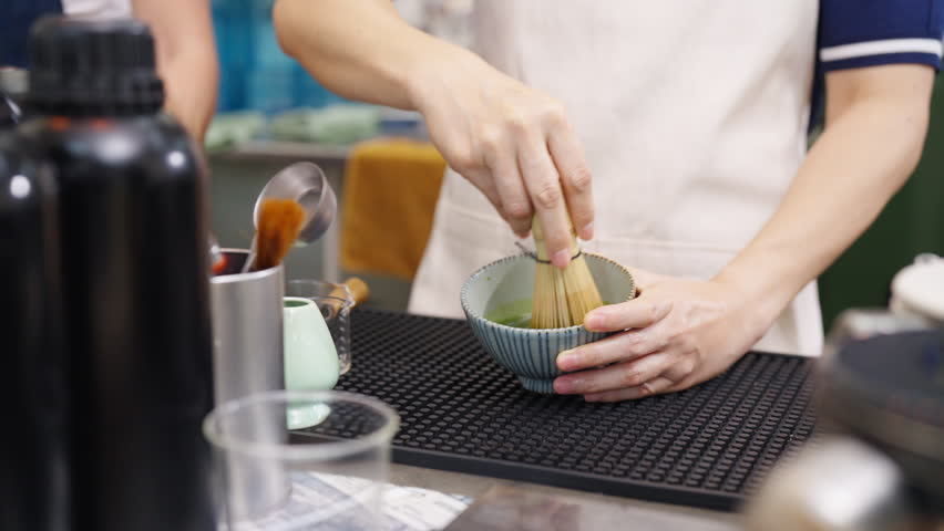 Small business entrepreneur coffee shop cafe restaurant. Asian woman barista preparing matcha green tea drink on bar counter. Female waitress working part time job serving beverage to customer.
