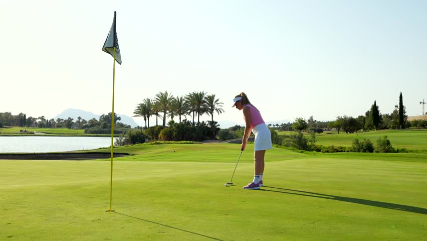 Female golfer executing precise putting strokes near serene lakeside green, showcasing golfing skill and concentration during summer day - Powered by Shutterstock - Get 15% off with code: PIKWIZARD15