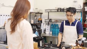 Small business entrepreneur barista coffee shop cafe restaurant. Customer tap credit card on card swipe machine making online banking payment buy coffee at cashier counter. Cashless payment technology - Powered by Shutterstock - Get 15% off with code: PIKWIZARD15