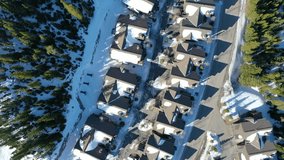 Overhead shot of peaceful snowy condos in Big Sky, Montana, nestled among pine forests, with winding snowy paths and mountain peaks in the distance—ideal for a cozy winter stay in the woods. - Powered by Shutterstock - Get 15% off with code: PIKWIZARD15