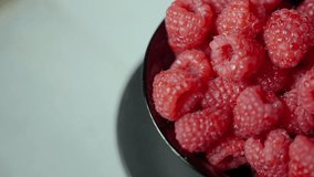 Close-up slow motion of fresh raspberries spinning in a bowl. One raspberry features a water droplet, top-down macro shot. - Powered by Shutterstock - Get 15% off with code: PIKWIZARD15