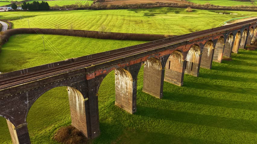 Scenic train viaduct surrounded by lush landscapes at sundown. Old train viaduct from drone perspective, set against scenic landscape. Famous places, historic district, transport structure crossing