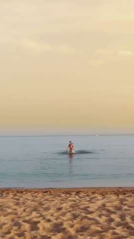 At sunset, a teenager girl in a bathing suit fun runs along the water on the beach. summer vacation at sea.