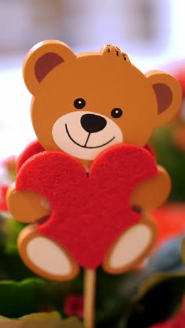 Happy Valentines Day. close-up. wooden toy teddy bear, with red felt heart in a flowerpot with flowers. gift, as an expression of feelings and love. festive decor, decorations for Valentines Day. Love