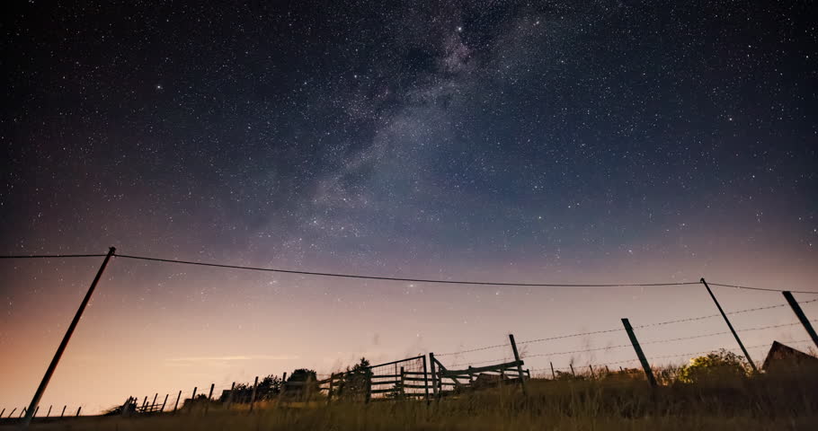 Milky Way star-trails and rural countryside tree silhouettes. Time-lapse video.