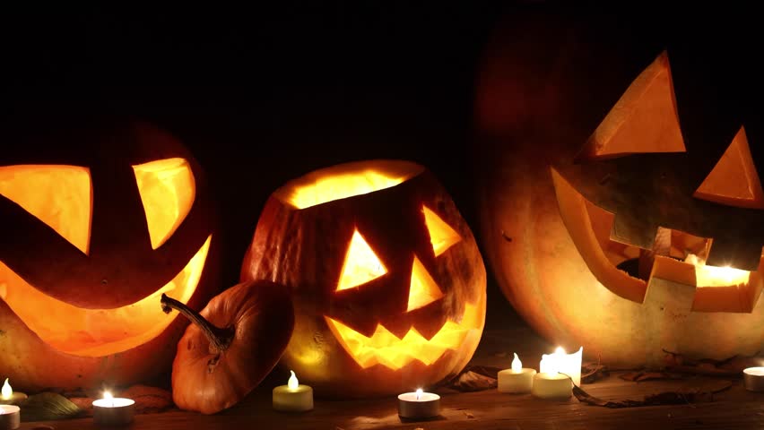 Happy Halloween. Jack o lantern glowing pumpkins with candles on table in dark scary backyard. Boo! Trick or treat! Spooky atmospheric Halloween night video