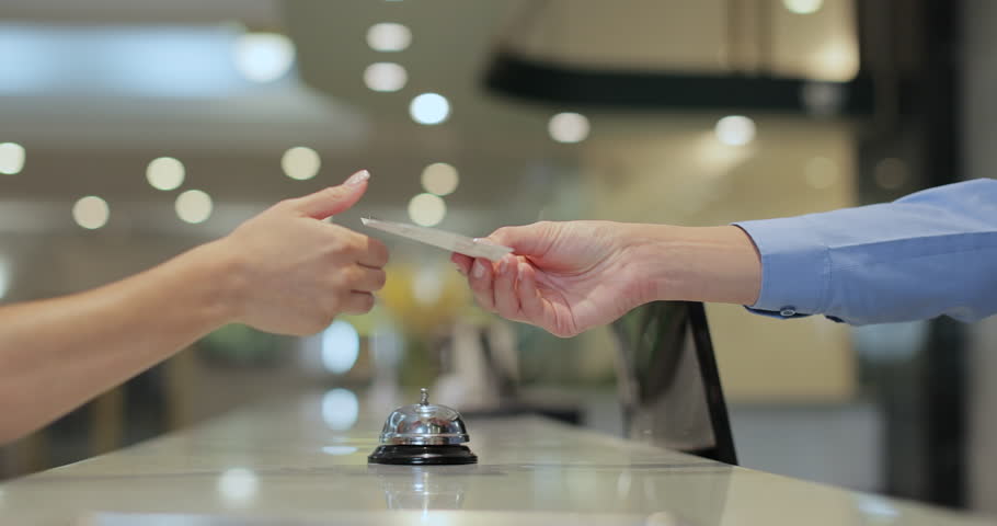 Close up of businesswoman hands getting room key at hotel reception. Hotel service.
