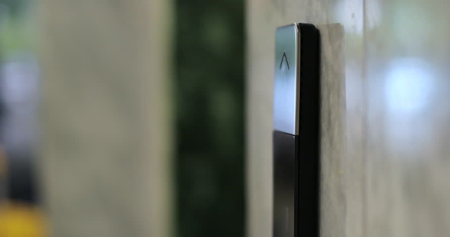 Man pushing elevator button in modern building or hotel. Male finger pressing lift button.