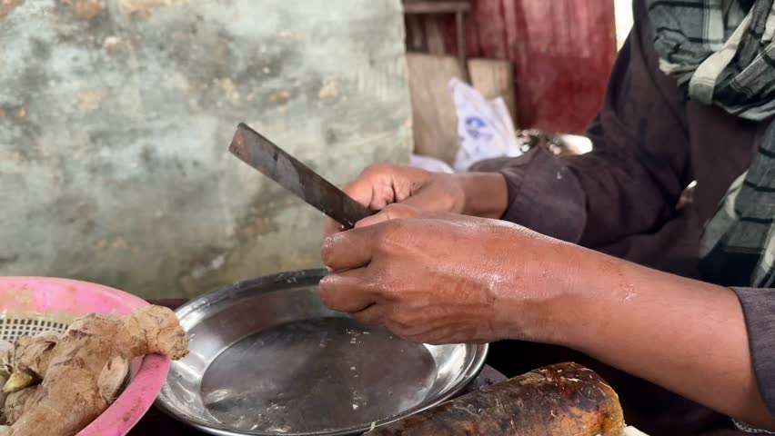 outdoor garlic peeling activity by laborer with knife.  close-up of hands peeling garlic with knife in open-air setting 