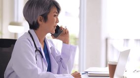Focused Asian doctor talking on smartphone offers virtual medical advice Professional healthcare communication and support - Powered by Shutterstock - Get 15% off with code: PIKWIZARD15