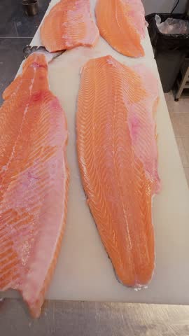 Close-up of fresh raw salmon fillet on a cutting board in a professional kitchen. Clean preparation and vivid texture of pink fish meat