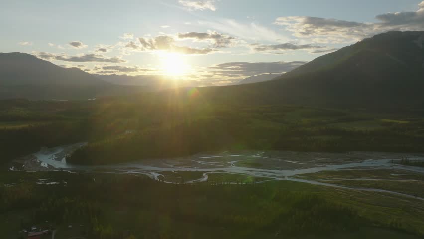 Dazzling Sun Shining Over Forested Mountains And Blaeberry River In The Canadian Rockies Near Golden, British Columbia, Canada. - aerial shot